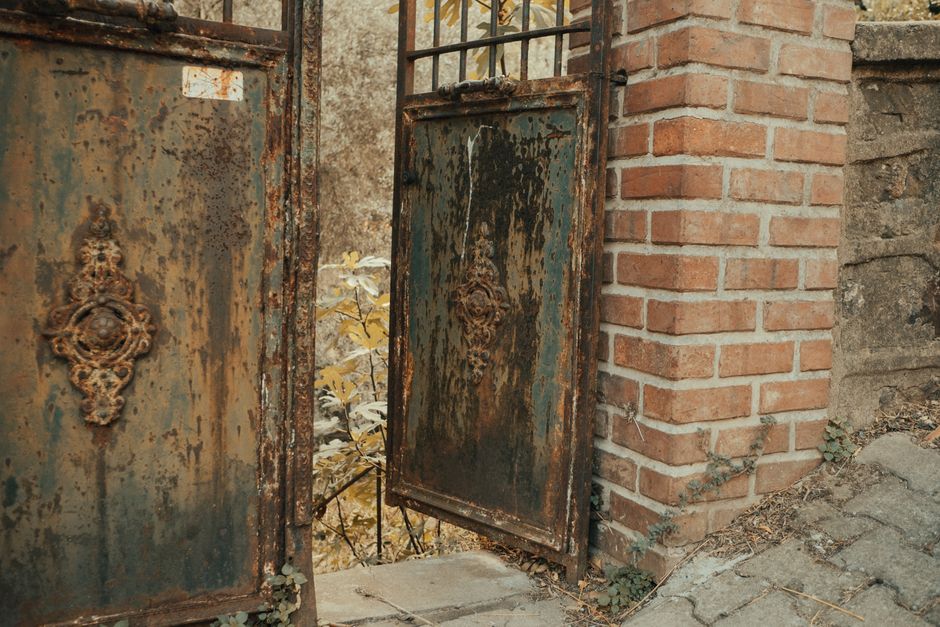 Metal gate with vertical pickets beside a brick wall
