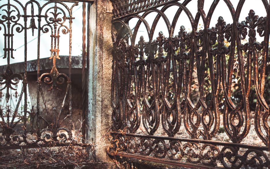 Decorative iron gate between two gate posts