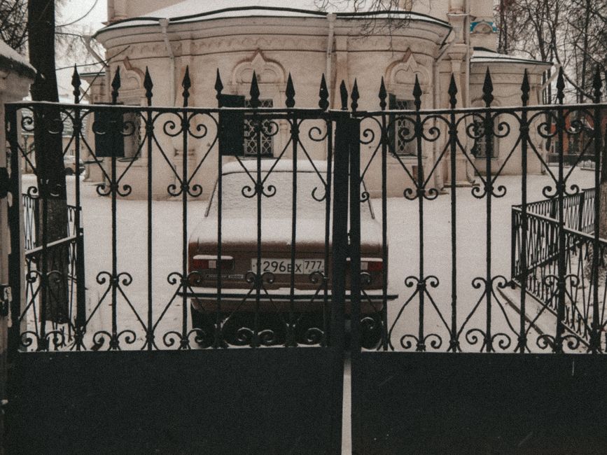 Black metal driveway gate closed across a residential driveway